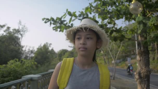 バックパック付きの麦藁帽子を被ったアジアの女性10代の若者がゆっくりと歩道を歩き 海岸沿いの美しい景色とマングローブの木をプーケットで楽しむ スローモーション — ストック動画