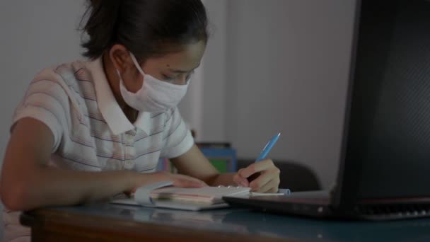 在Covid 19大流行期间 带着防护面具的亚洲可爱女孩带着视频电话从家里学习 母亲戴着防护面具走近学校 在家里教女儿上网学习 用笔记本电脑授课 — 图库视频影像