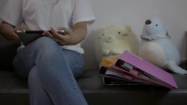 Deri koltukta oturan ve COVID-19 salgını sırasında evdeki birçok belgeyle dijital tablet kullanan sıradan bir kadın. Evden çalış.. 