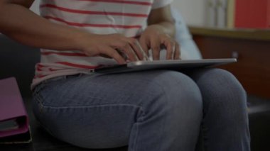 Oturma odasında oturan ve evde sosyal medyada dijital tablet üzerinde çalışan bir kadın. Covid-19 durumu sırasında veri takibi ve haberleşme cihazı ile günlük haberler. Evden çalış..