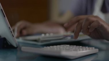 Kadın hesap bakiyesini kapat ve evdeki oturma odasındaki harcamaları hesapla. Ev hanımı hesap makinesiyle çalışıyor ve karantina sırasında COVID-19 salgınıyla birlikte masaya not alıyor. Evden çalış..