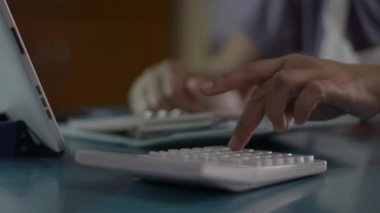 Kadın hesap bakiyesini kapat ve evdeki oturma odasındaki harcamaları hesapla. Ev hanımı, COVID-19 salgınıyla karantina sırasında masada hesap makinesi ve dijital tabletle çalışıyor. Evden çalış..