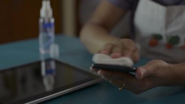 Coronavirüs veya COVID-19 salgınının yayılmasını önlemek için cep telefonu ve dijital tablet yüzeylerindeki kadın temizlik ve dezenfeksiyonu.