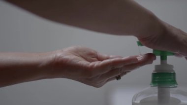 Koronavirüsün yayılmasını önlemek için elini temizlemek için sıvı sabun makinesi kullanan kişi. COVID-19 salgını sırasında ellerini yıkamadan önce sabunla ovuşturan bir kadını kapat..