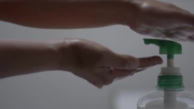 Koronavirüsün yayılmasını önlemek için elini temizlemek için sıvı sabun makinesi kullanan kişi. COVID-19 salgını sırasında ellerini yıkamadan önce sabunla ovuşturan bir kadını kapat..