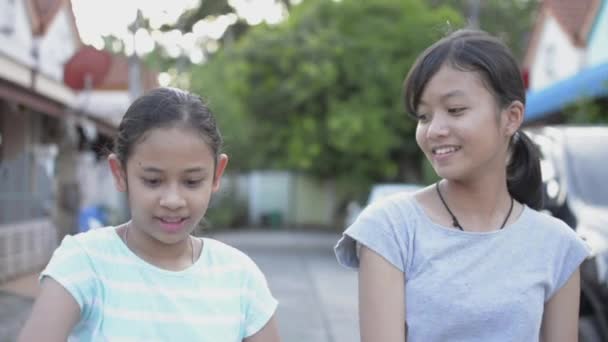 かわいいアジアの女の子と彼女の妹は 住宅団地の通路に立っている間に素敵なダンスを練習するのを楽しんでいます 居住地での休暇中の女性のティーンエイジャーの活動 スローモーション — ストック動画