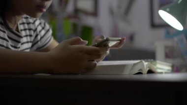 İlkokul öğrencisi kız cep telefonu kullanıyor ve sınav sırasında önemli içerikleri araştırıyor. Evde karantina sırasında cep telefonuyla sosyal medyada sohbet eden küçük bir kız..