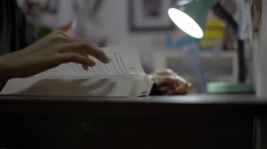 Ders kitabının sayfalarını çeviren bir kızın elini kapat ve masada kitap okurken parmaklarını sayfa boyunca hareket ettir. Liseli kız evdeki karantina sırasında sınava çalışıyor..