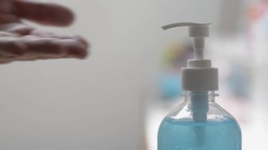 Adam ellerini alkol jeliyle temizliyor ve COVID-19 salgını sırasında koruyucu yüz maskesi takıyor. Virüsün yayılmasını önlemek için tıbbi maske takmadan önce insanların ellerini dezenfektan sürerken kapatın. Coronavirus koruması. 