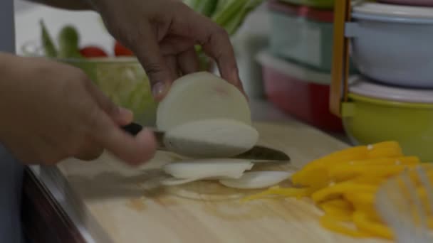 家庭主妇在准备早餐的时候用刀片在木板上切洋葱 关闭妇女的手切片洋葱沙拉在桌子上与健康的食物在厨房 侧视图 — 图库视频影像