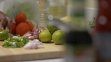 Ev hanımı ahşap kesme tahtasındaki bıçakla limon kesiyor. Mutfaktaki masada baharatlı salata için malzeme hazırlayan kadın ellerini kapat. Yavaş çekim çekim..