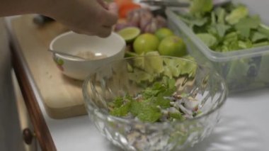 Kadın şef bütün malzemeleri karıştırmak için büyük bir kaseye koyuyor. Ev hanımının elleri mutfakta baharatlı tavuk salatası hazırlıyor.. 