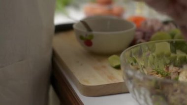 Kaşık ve çatal kullanan kadın aşçı bütün malzemeleri büyük bir kasede karıştırıyor. Mutfakta baharatlı tavuk salatası hazırlayan kadının elleri..