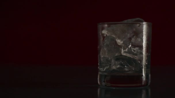 氷のキューブでガラスにソーダ水を注ぐを閉じます 氷とガラスの泡で炭酸飲料 夜のテーブルの上で冷たい飲み物のカップ — ストック動画