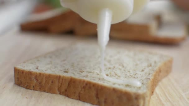 在木板上的一片全麦面包上用瓶子浇甜的浓缩牛奶 — 图库视频影像