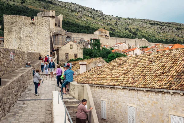 Turistas visitando las famosas murallas de la ciudad de Dubrovnik que rodean el casco antiguo de Dubrovnik — Foto de Stock