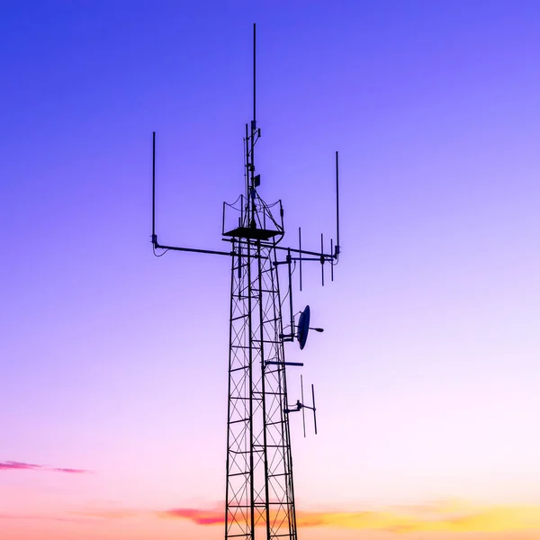 Kolumn med radiosändare mot solnedgången färgar himlen — Stockfoto