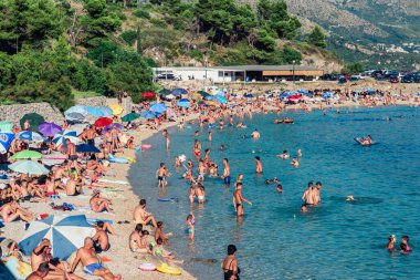 Kupari, Hırvatistan - 5 Ağustos 2016: Kupari, Dubrovnik yakınlarında insanların turkuaz suda yıkandığı ve kumlu sahilde güneşlendiği bir yer