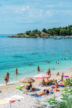 MLINI, CROATIA - 6 AĞUSTOS 2016: Mlini, Dubrovnik yakınlarında insanların turkuaz suda yüzdüğü ve kumlu sahilde güneşlendiği bir tatil beldesi.