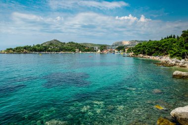 MLINI, CROATIA - 6 AĞUSTOS 2016: Mlini, Dubrovnik yakınlarında insanların turkuaz suda yüzdüğü ve kumlu sahilde güneşlendiği bir tatil beldesi.