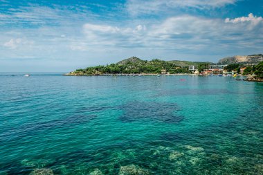 MLINI, CROATIA - 6 AĞUSTOS 2016: Mlini, Dubrovnik yakınlarında insanların turkuaz suda yüzdüğü ve kumlu sahilde güneşlendiği bir tatil beldesi.