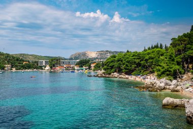 MLINI, CROATIA - 6 AĞUSTOS 2016: Mlini, Dubrovnik yakınlarında insanların turkuaz suda yüzdüğü ve kumlu sahilde güneşlendiği bir tatil beldesi.