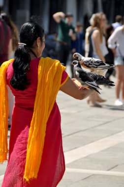 Venedik 'in en ünlü meydanında güvercinli bir kadın. Venedik 'e yılda 20 milyondan fazla turist geliyor.