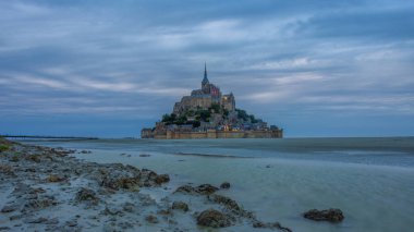 Mont saint michel aydınlanmış mimari panoramik güzel kartpostal görüntüsü Dusk, Summer Low Tide 'da köprüden yansıyan yansımayla, Fransa