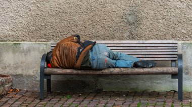 Eski tarihi Salzburg kasabasında bir bankta uyuyan evsiz bir adam.