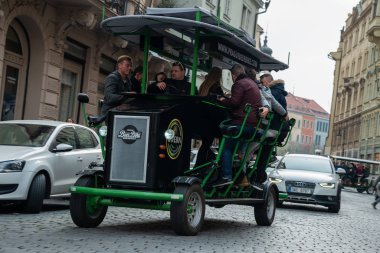 People riding the pedaling bar, Party bike or Beer Bike through the old town of Prague