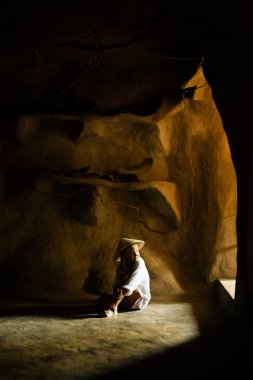 Vietnamlı küçük bir kız. Yüzünde güneş ışığı olan karanlık bir yerde.