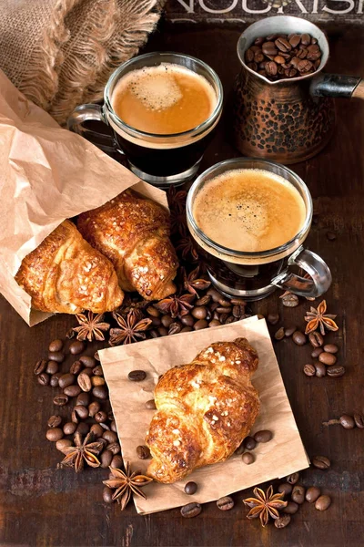 Glass  mug of coffee and croissant on wooden table — Stock Photo, Image