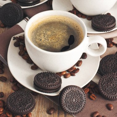 Çikolatalı kurabiye ve ahşap masada bir fincan aromatik kahve.