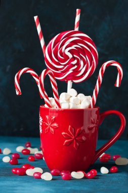 Şenlikli kırmızı ve beyaz nane şekerleri ve bardakta lokum.