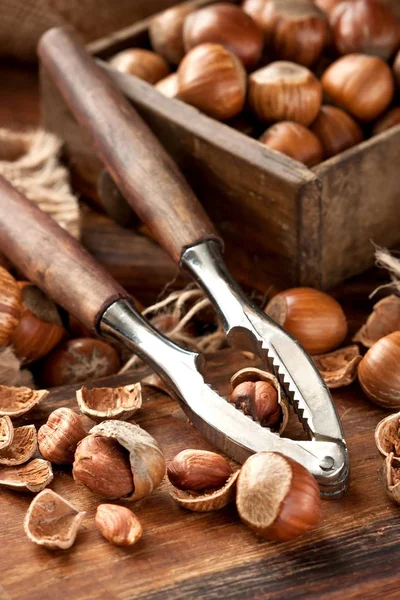 Haselnuss mit Nussknacker auf Holzbrett — Stockfoto