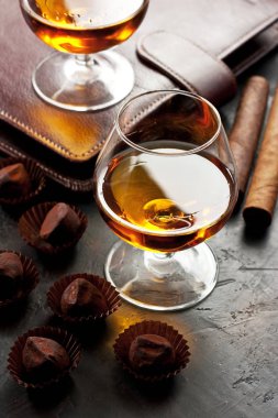 Koyu masada bir bardak viski, çikolatalı yer mantarı ve puro