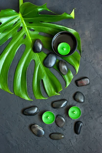 Flat lay composition with  leaf of monstera plant and spa stones — Stock Photo, Image