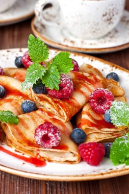 Küçük ev yapımı krep yığını, böğürtlen ve ahşap masada şurup.