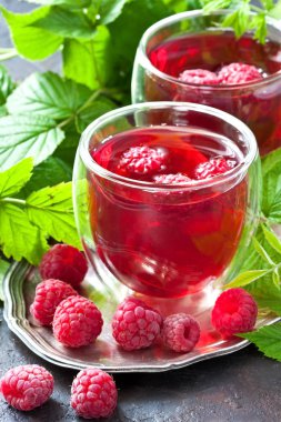 Koyu beton arka plan üzerinde ahududu ve yeşil yaprakları ile ferahlatıcı içecek, seçici odak