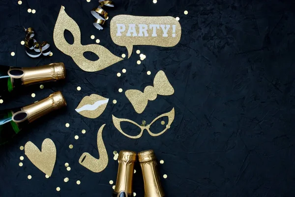 Carnival party celebration concept with elegant  masks  and bottle of champagne  over dark  background . Top view with copy space