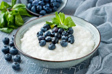 Vanilyalı sütlaç ya da taze yaban mersinli yulaf lapası. Sığ alan derinliğinde seçici bir odak noktası.