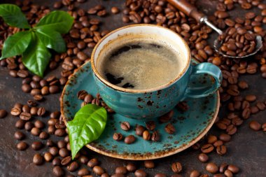 Kahveli seramik fincan ve koyu arkaplanda taze yapraklar, seçici odak alan derinliği sığ