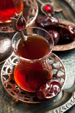 Geleneksel bakır servis setinde tarihi meyvelerle dolu cam bardakta Türk çayı, sığ alan derinliğinde seçici bir odak