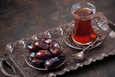 Geleneksel bakır servis setinde tarihi meyvelerle dolu cam bardakta Türk çayı, sığ alan derinliğinde seçici bir odak