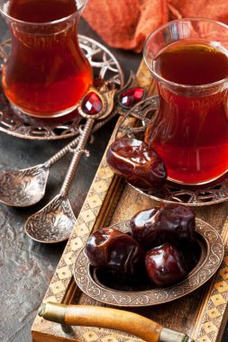 Geleneksel bakır servis setinde tarihi meyvelerle dolu cam bardakta Türk çayı, sığ alan derinliğinde seçici bir odak