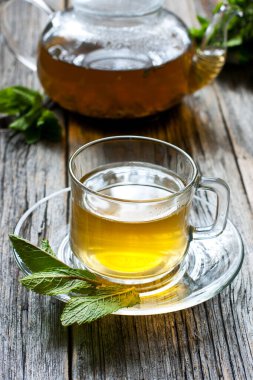 Ahşap arka plan üzerinde cam bardak sıcak nane çayı, alan sığ derinliği ile seçici odak