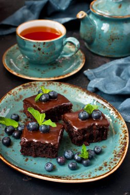 Çikolatalı kek. Tatlı. Üzerinde yabanmersini ve çay fincanı var.