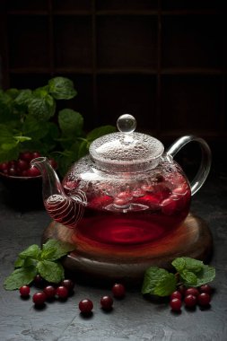 Koyu taş masada cam çaydanlıkta çilek çayı. Sığ alan derinliğinde seçici bir odak.