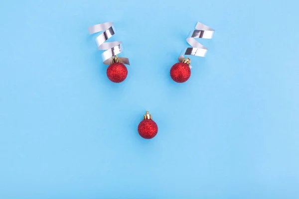 Concepto de renos navideños hecho de adorno de bauble rojo y cinta de plata sobre fondo azul pastel . — Foto de Stock