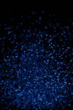 Soyut mavi simli konfeti siyah arkaplanda parıldıyor.